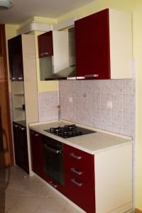 a kitchen with red cabinets and a stove top oven at Apartman Klara in Karlovac