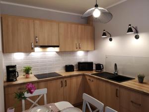 a kitchen with wooden cabinets and a table with a dining room at Apartament Malinowy Zakątek Triventi Mountain Residence in Karpacz