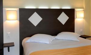 uma cama com duas almofadas brancas e uma cabeceira preta em Comfort Hotel Saintes em Saintes