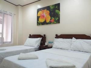 duas camas num quarto com um quadro na parede em Devayn's Inn em El Nido