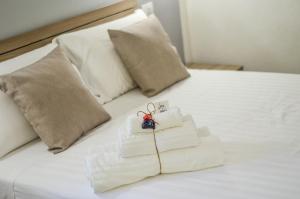een stapel handdoeken op een wit bed met kussens bij Vicoli di Napoli B&B in Napels