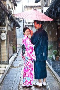 a man and woman standing under an umbrella in the rain at Yamagata Kyomachi Hatago Gojo Nishinotoin in Kyoto