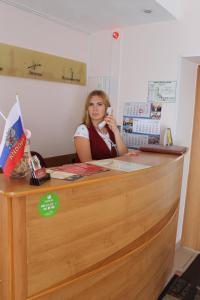 Una donna che parla al telefono alla scrivania di Comfort Hotel a Lipetsk