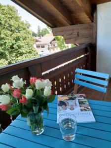 un tavolo blu con un vaso di fiori e un libro di Appartements Apfelblüte a Bad Feilnbach