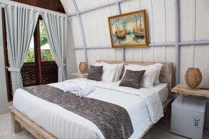 a bedroom with a large white bed with a picture on the wall at Papa Sun Villas in Nusa Penida