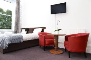 a living room with a couch, chair, table and tv at Park View House Hotel in Edinburgh