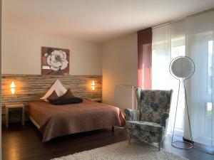 a bedroom with a bed and a chair and a fan at Designhotel Im Südfeld in Kamen