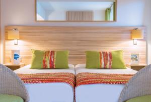 a hotel room with two beds and two chairs at Hôtel Vacances Bleues Delcloy in Saint-Jean-Cap-Ferrat