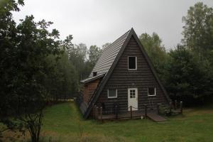 une grande maison avec un toit en gambrel sur un champ dans l'établissement Äventyrscampen, à Sjöbo