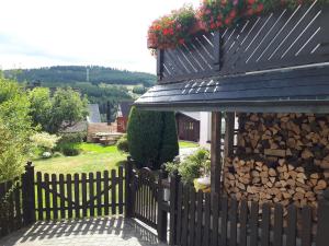 uma cerca com uma pilha de lenha ao lado de uma casa em Ferienwohnungen Luge - Winterberg em Winterberg