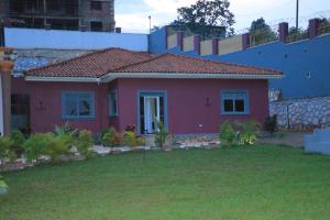 a small red house with a green yard at Mutundwe Villa in Kampala