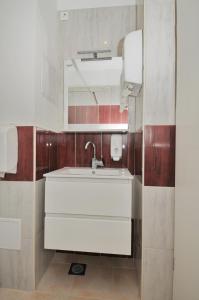 La salle de bains est pourvue d'un lavabo blanc et d'un miroir. dans l'établissement Oasis hostel, à Split