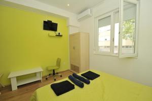 - une chambre avec un lit jaune, un bureau et une fenêtre dans l'établissement Oasis hostel, à Split