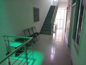 un pasillo con sillas y escaleras con luces verdes en Sai Guest House, en Pathankot