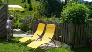 duas cadeiras amarelas num quintal ao lado de uma cerca em Haus Bergkristall em Bad Hindelang