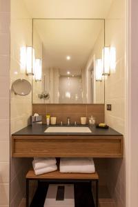Appartements Chais Monnet في كونياك: حمام مع حوض ومرآة كبيرة