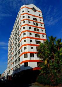a tall white and orange building with a palm tree at Kawan Hotel in Sibu