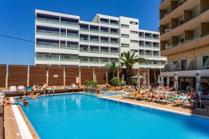 a pool in front of a hotel with people sitting in chairs at Rhodos Horizon Blu-Adults Only in Rhodes Town