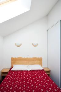 een slaapkamer met een bed met een rode deken bij travelski home select - Résidence Les Hauts de Valmeinier 4 stars in Valmeinier