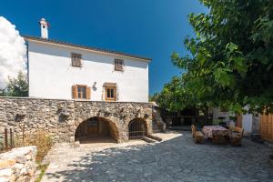 ein großes weißes Haus mit einem Steingebäude in der Unterkunft Villa Nadia in Dobrinj