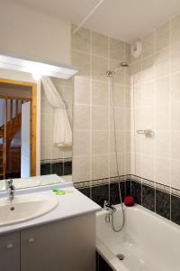 een badkamer met een wastafel, een bad en een douche bij travelski home select - Résidence Les Hauts de Valmeinier 4 stars in Valmeinier