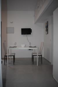 Biały stół z krzesłami i telewizor na ścianie w obiekcie COSTA DEL SILENCIO - 28/5 UP w mieście Costa Del Silencio