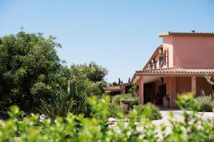 a house with trees and plants in the foreground at Hotel Su Giudeu in Chia