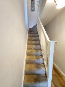 a staircase with white railings and wood floors at Beautiful 3 Bedroom House at the Sea Front - Amazing Location in Southend-on-Sea