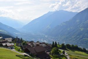 a village in a valley with mountains in the background at Hütterhof in Lagundo