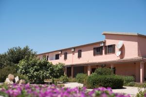 a building with pink flowers in front of it at Hotel Su Giudeu in Chia