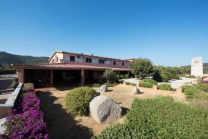 a building with a garden with rocks and flowers at Hotel Su Giudeu in Chia