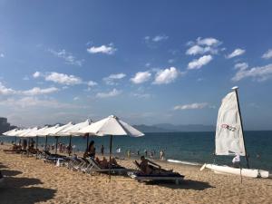 un groupe de personnes assises sur une plage avec des parasols dans l'établissement Majestic Premium Hotel, à Nha Trang
