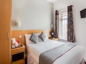 Un dormitorio con una cama grande y una ventana en OYO London Guest House en Londres