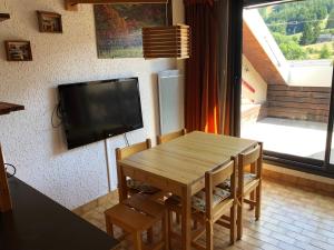 sala de estar con mesa de madera y TV de pantalla plana en Duplex 6 à 8 couchages calme avec solarium plein Sud, en Ancelle