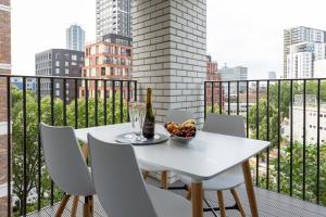 - une table et des chaises blanches sur un balcon avec une bouteille de vin dans l'établissement Luxury Central London Apartment, à Londres