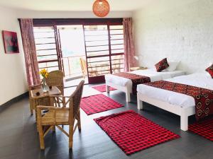 a room with two beds and a table and chairs at Koi Koi, Fort Portal in Fort Portal