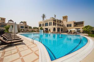 a large swimming pool with chairs and a building at Roda Beach Resort in Dubai