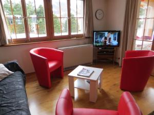 a living room with red chairs and a tv at Chalet Petite Fleur in Adelboden