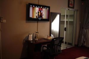a room with a desk with a television on the wall at Triple Palms Bed and Breakfast in Gaborone