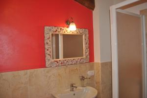 ラポラーノ・テルメにあるAntico Granaioneのバスルーム(洗面台、赤い壁の鏡付)