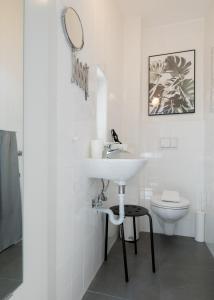 La salle de bains blanche est pourvue d'un lavabo et de toilettes. dans l'établissement Baixa24 •P1L• Amplo estúdio na baixa com varanda, à Porto