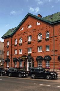 un edificio de ladrillo rojo con coches aparcados delante de él en Grand Hotel Perm en Perm
