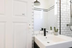 a white bathroom with a sink and a white tiled wall at Baixa24 · City Center Private Sun Deck Apartment in Porto