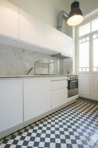 a kitchen with white cabinets and a checkered floor at Baixa24 · City Center Private Sun Deck Apartment in Porto