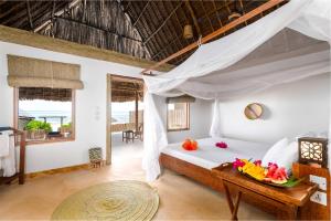a bedroom with a bed and a table with fruit on it at Zanzibar Sunrise at Bandas in Matemwe