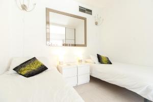 a white bedroom with two beds and a mirror at PYR Private Apartment SUNNY pool SIDE in Fuengirola