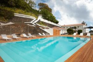 a swimming pool with chairs and a building at Quinta da Abelheira in Ponta Delgada
