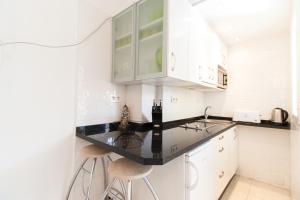 una cucina con armadi bianchi e piano di lavoro nero di PYR Private Apartment SUNNY pool SIDE a Fuengirola