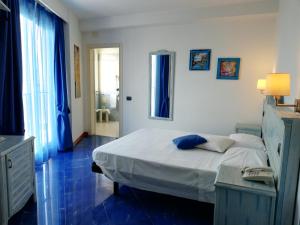 um quarto com uma cama branca e pisos azuis em Blue Moon Hotel em Pantelleria