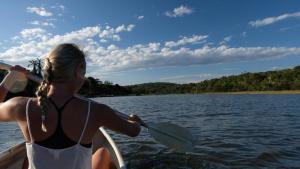 a woman in a boat with a paddle in the water at Buccaneers on the beach, Chintsa, South Africa in Chintsa